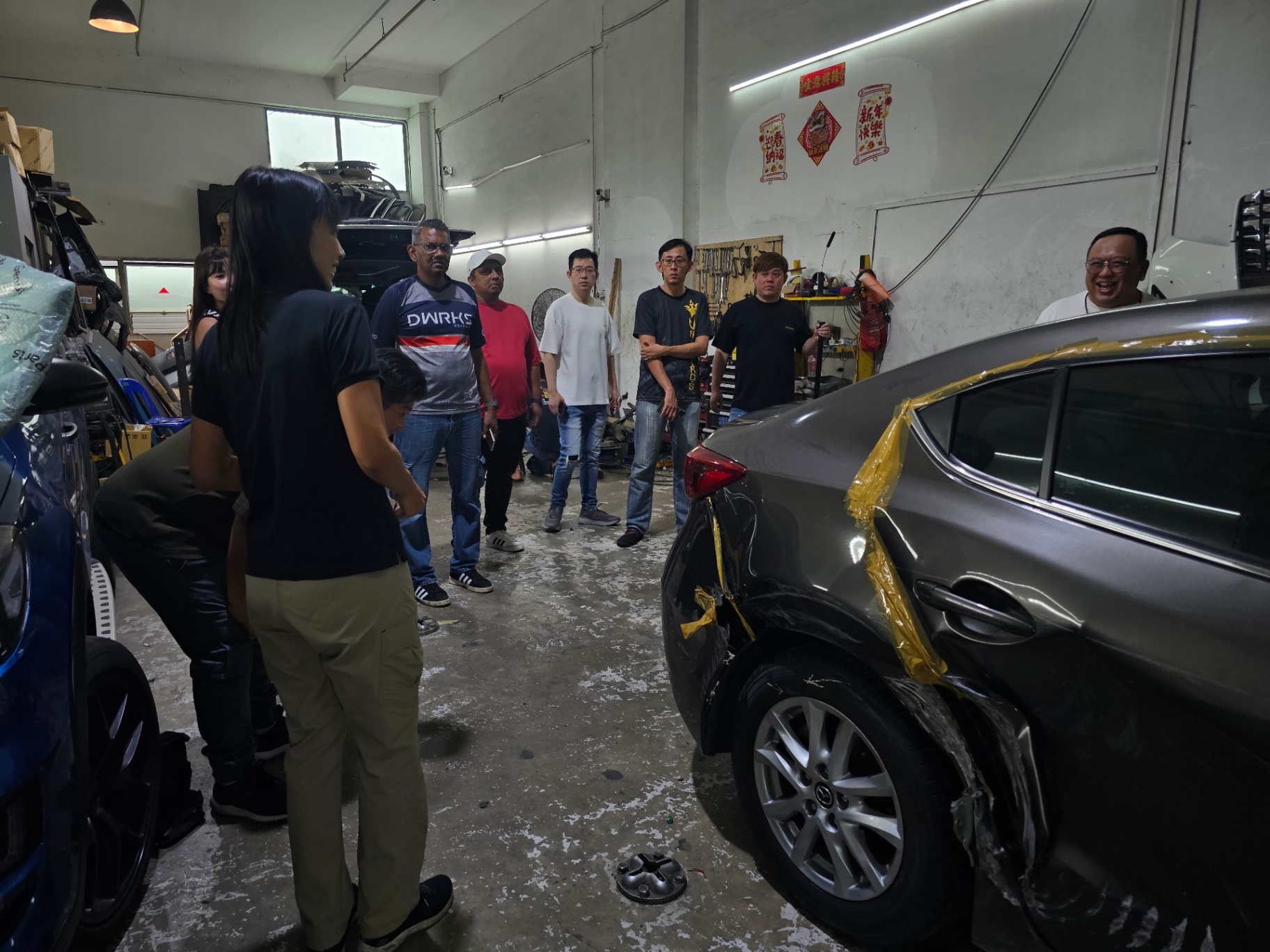 Igive team visiting a repair workshop and discussing a damaged vehicle with participants.